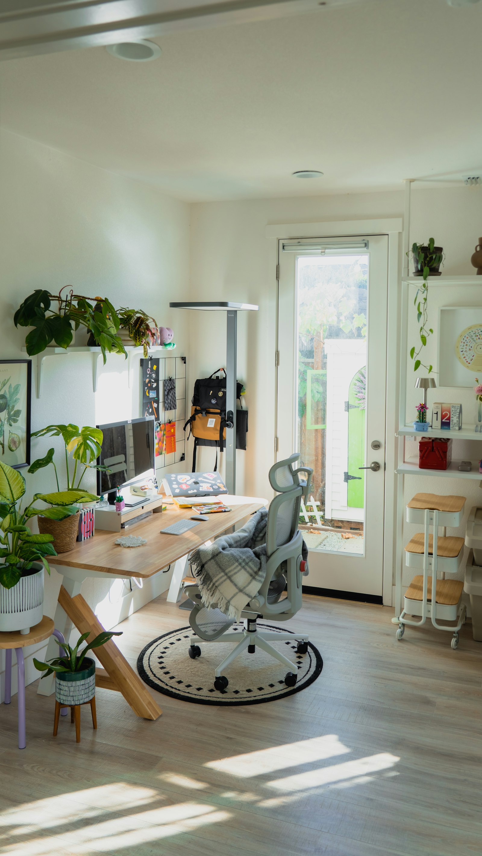 A bright, comfortable home office with a standing desk and plants